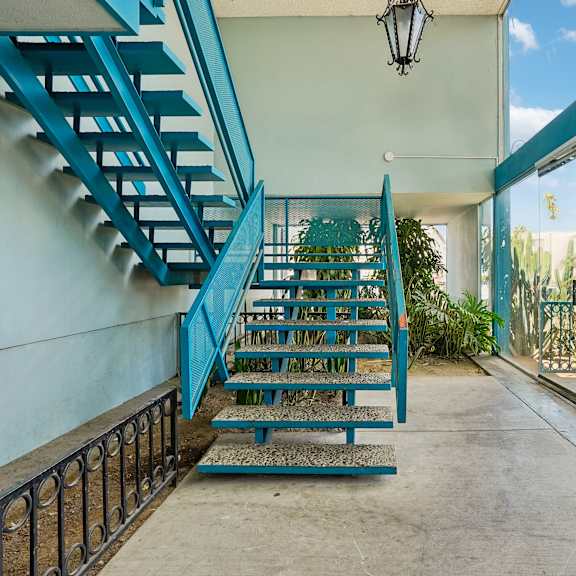 a blue staircase with a black railing.