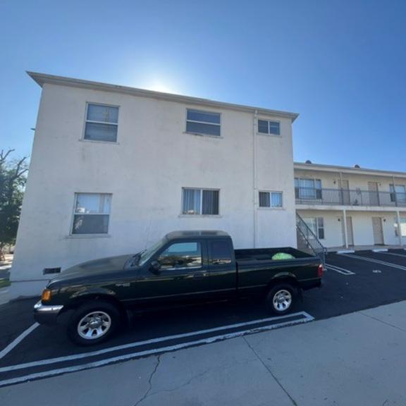 a black pickup truck is parked in a parking lot in front of a white building.