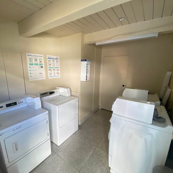a laundry room with a washer, dryer, and ironing board.