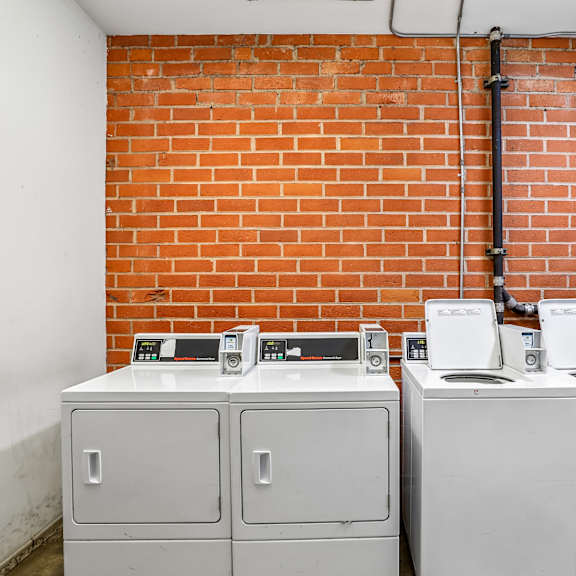 three white electrical boxes are on a brick wall.