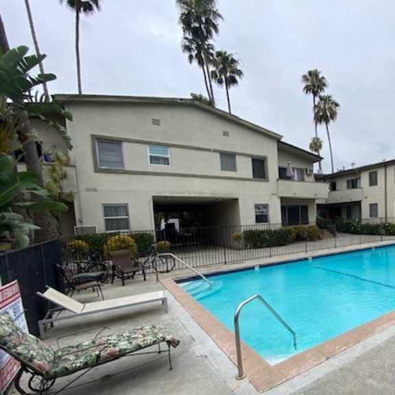 a pool in front of a building with palm trees.