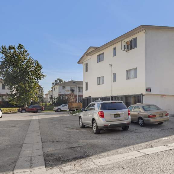 two cars are parked in a parking lot in front of a white building.