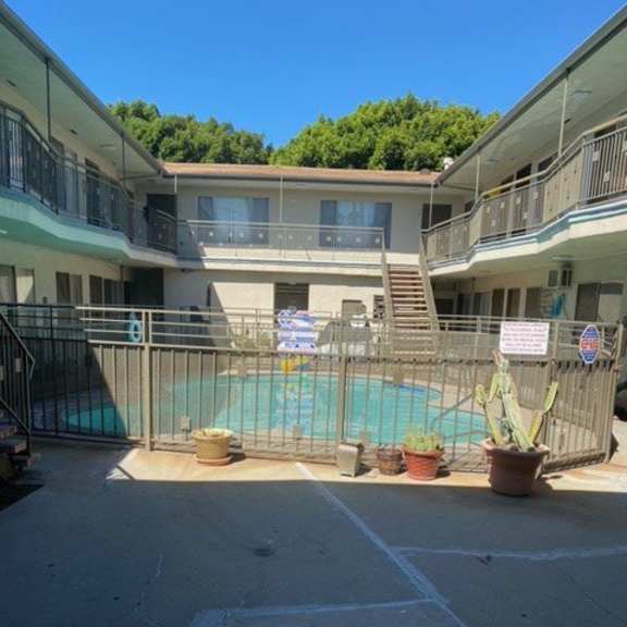 a pool surrounded by a fence and a building in the background.