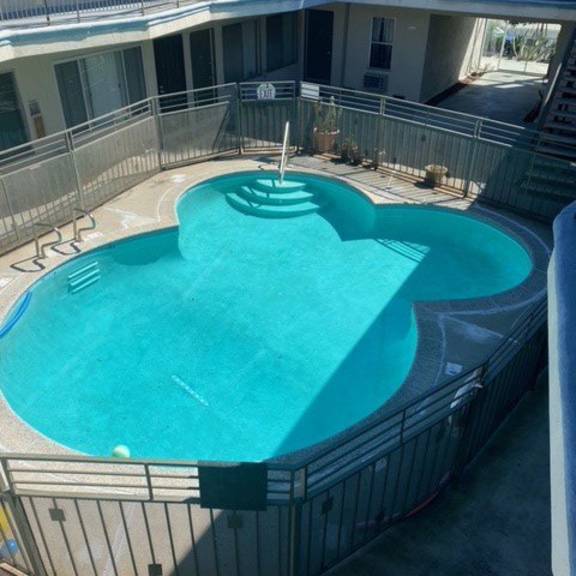 a heart-shaped pool in a courtyard surrounded by a metal fence.