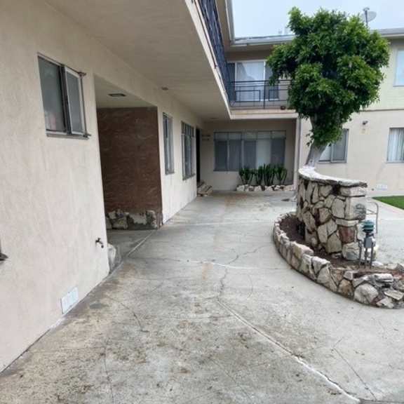 a concrete patio with a stone wall and a tree.