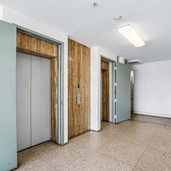 a hallway with a white wall and a tiled floor.