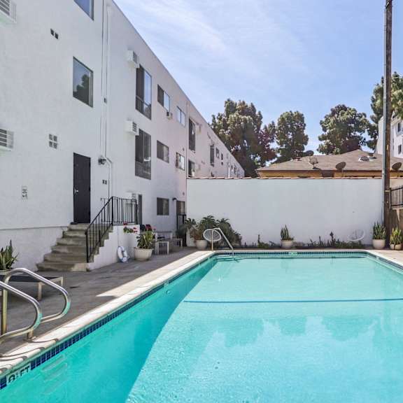 a swimming pool in a residential area with a white building and a black fence.