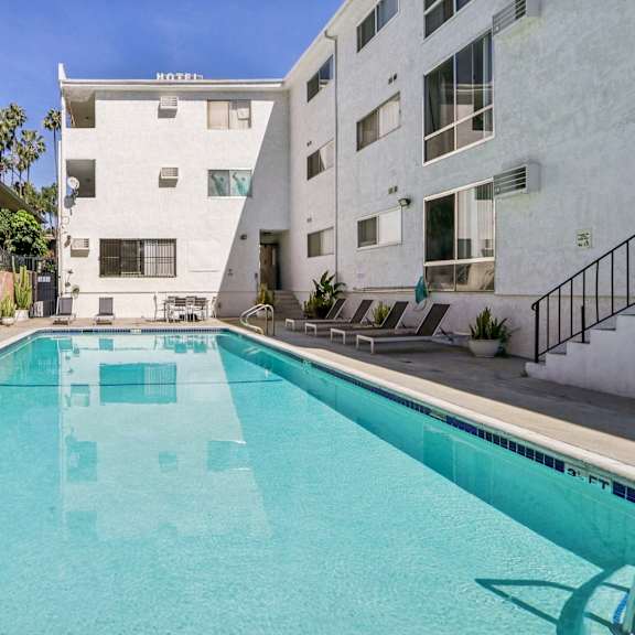 a swimming pool in front of a white building with a black fence.