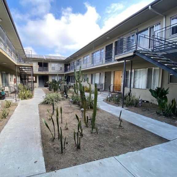a courtyard with a concrete floor and a variety of plants and cacti.