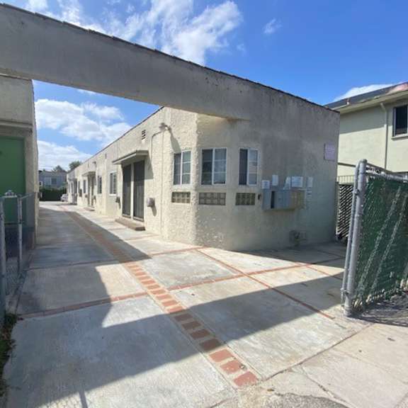 a long concrete walkway leads to a green door.