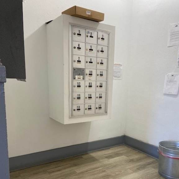 a metal bucket is on the floor next to a wall with a panel of switches.