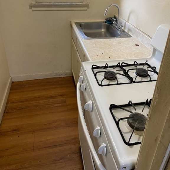 a white gas stove with a sink in the corner.