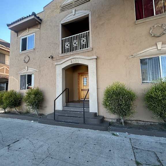 a beige building with a balcony and a doorway.