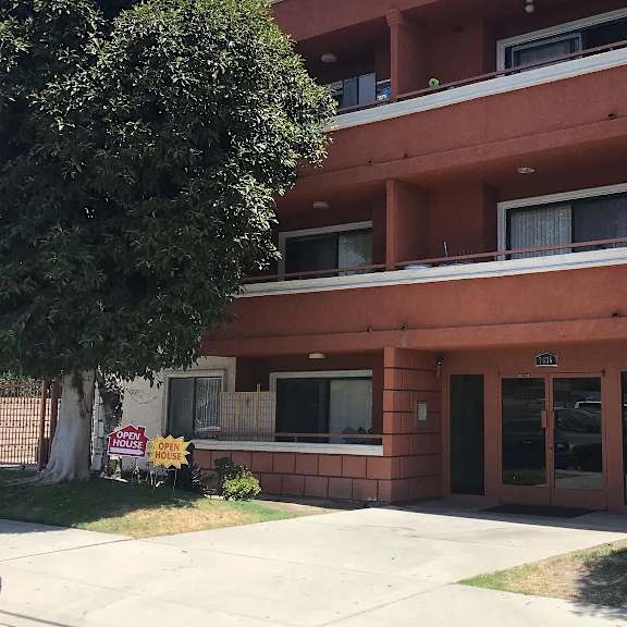 a multi-story apartment building with a "for rent" sign in front.