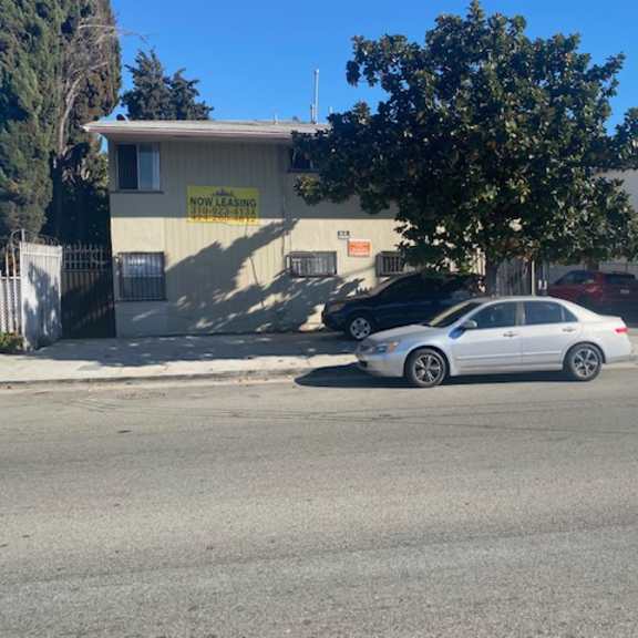 a car is parked in front of a building with a "now leasing apartments" sign.
