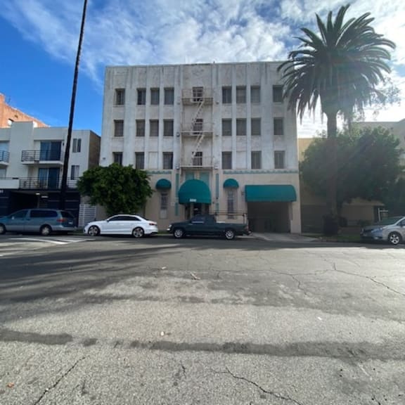 a white car is parked in front of a building with a blue awning.