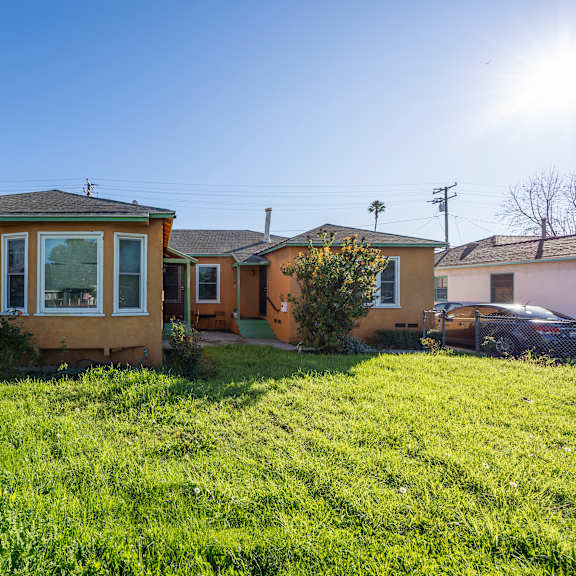 a yellow house with a green lawn in front.