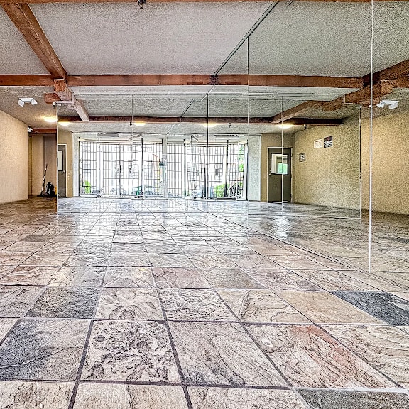 a large, empty room with marble flooring and wooden beams on the ceiling.