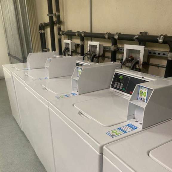 a series of industrial washing machines are lined up in a row.