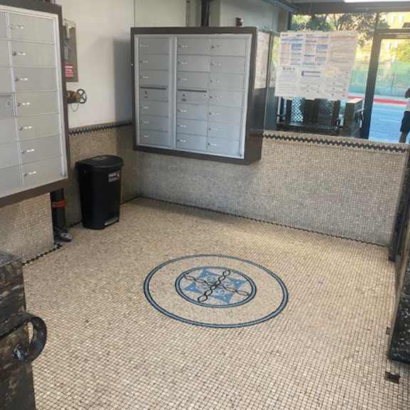 a room with a mosaic floor and a trash can.