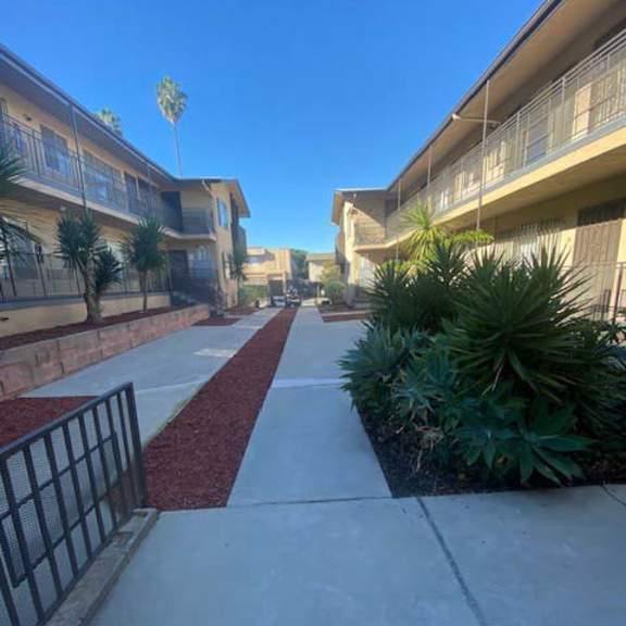 a red brick pathway leads to a building with a black gate on the left.