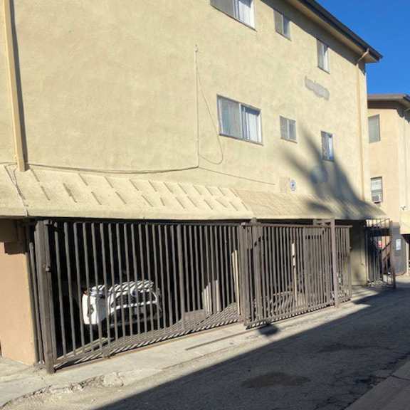 a car is parked behind a metal gate on a street.