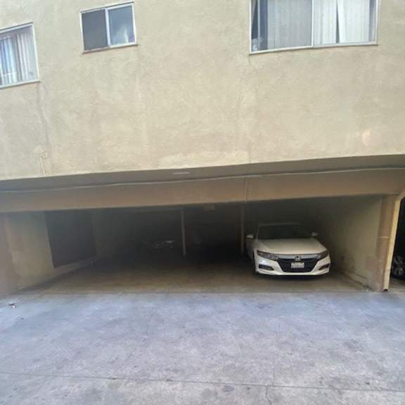 a white car is parked in a garage under a building.