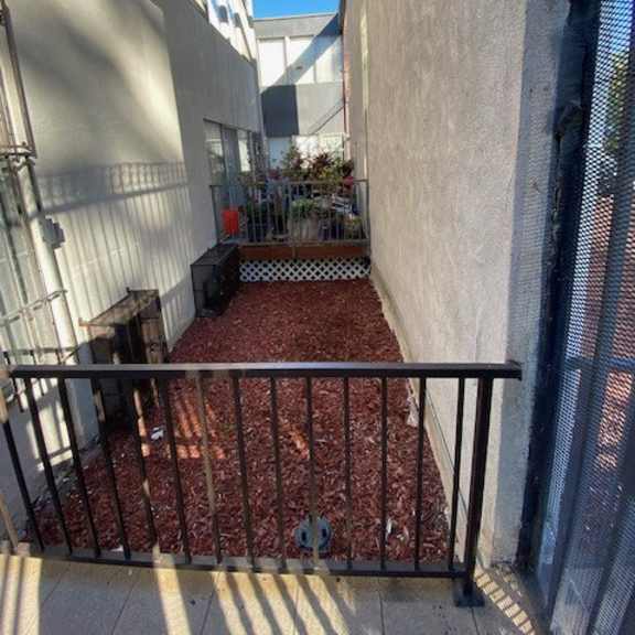 a small patio with a metal railing and a red brick floor.