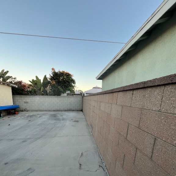 a backyard with a concrete floor and a brick wall.