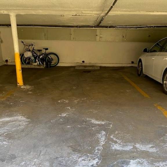 a parking garage with several cars parked and green pillars.