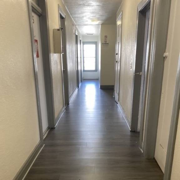 a long hallway with doors on both sides and a light at the end.