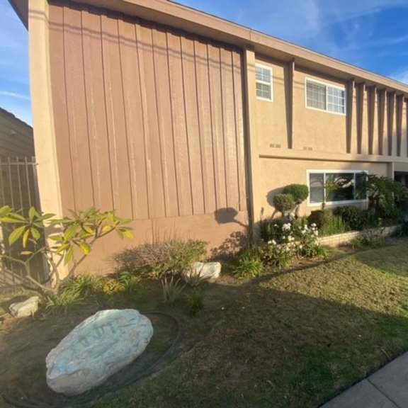 a building with a brown facade and a large rock in the front yard.