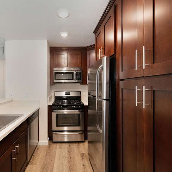 a kitchen with wooden cabinets and stainless steel appliances at croft plaza apartments, west hollywood, ca 90069