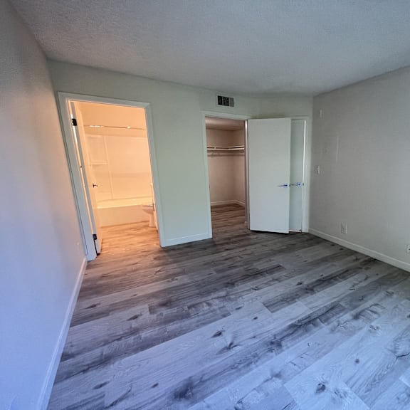 Thumbnail 5 of 7 A room with a wooden floor and white walls.