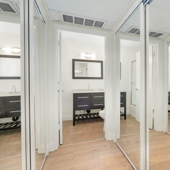 Thumbnail 2 of 10 A bathroom with a mirrored wall and a sink.