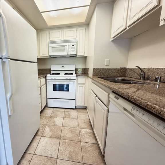 Thumbnail 23 of 25 A kitchen with white appliances and a tiled floor.