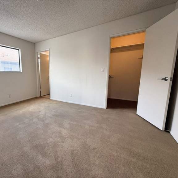 Thumbnail 17 of 25 A room with carpeted floor, two doors, and a window.