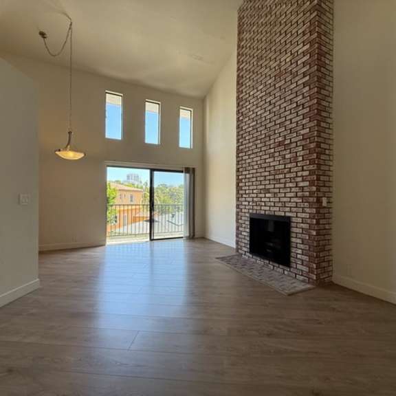 Thumbnail 5 of 17 A room with a fireplace and a view of a building outside the window.