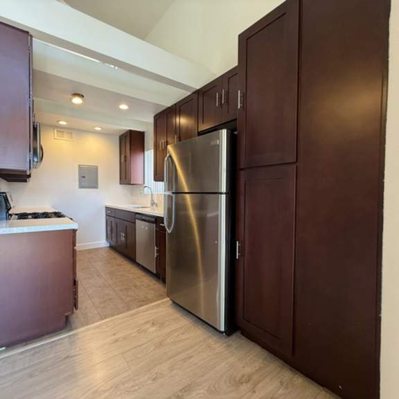 Thumbnail 16 of 17 A kitchen with a refrigerator, cabinets, and a counter.