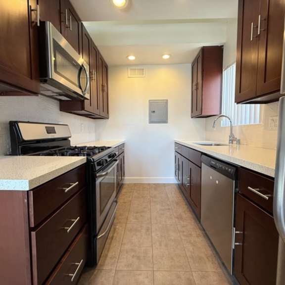 Thumbnail 10 of 17 A kitchen with brown cabinets and stainless steel appliances.