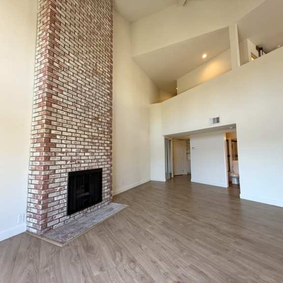 Thumbnail 4 of 17 A room with a fireplace and wooden floors.