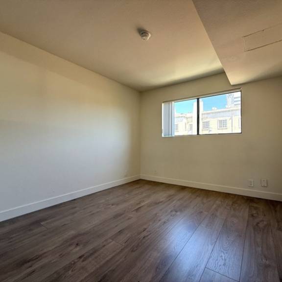 Thumbnail 14 of 17 A room with a window and wooden flooring.