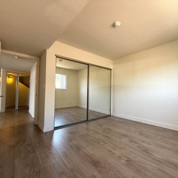 Thumbnail 15 of 17 A room with a sliding glass door and wood flooring.