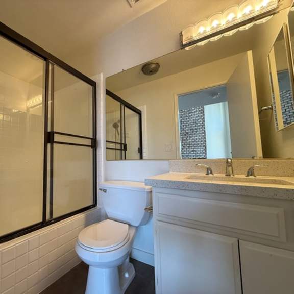 Thumbnail 12 of 17 A white toilet sits in a bathroom with a sink and mirror.
