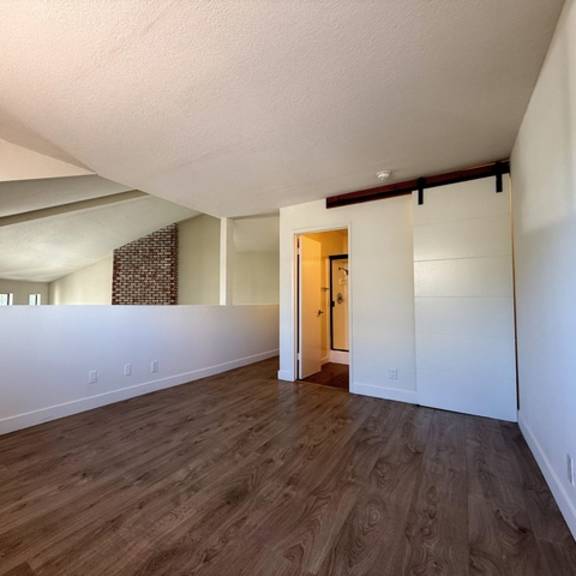 Thumbnail 9 of 17 A room with wooden flooring and a door on the right side.