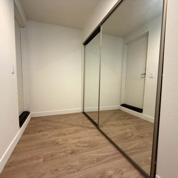 Thumbnail 7 of 17 A hallway with a mirror on the wall and wooden flooring.