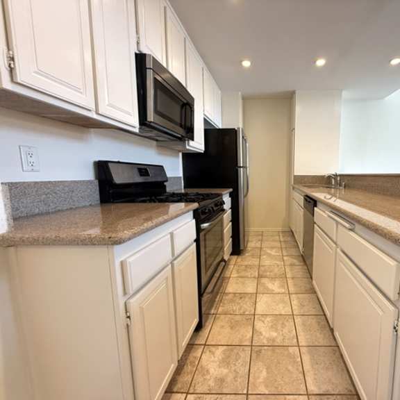 Thumbnail 16 of 20 A kitchen with white cabinets and black appliances.