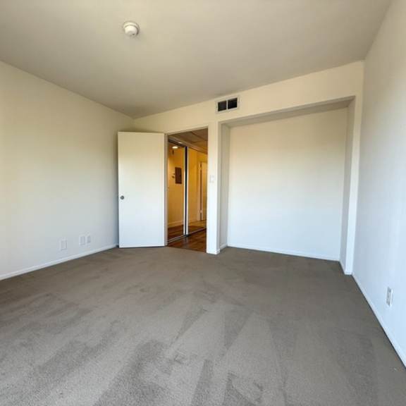 Thumbnail 19 of 20 A room with a carpeted floor and a doorway leading to another room.