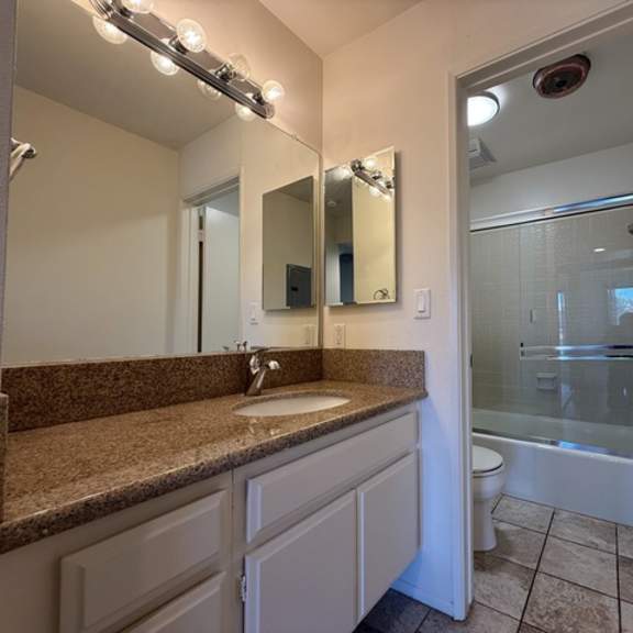 Thumbnail 20 of 20 A bathroom with a sink, mirror, and shower.