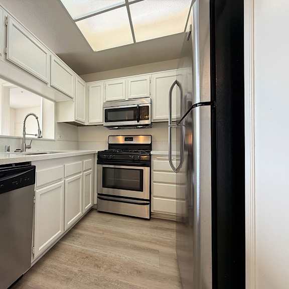 Thumbnail 8 of 29 A kitchen with white cabinets and stainless steel appliances.